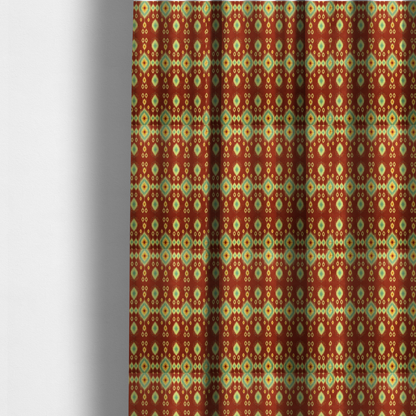 the fabric used to create these made-to-measure curtains is a print featuring a repeating vertical ikat pattern. The design showcases distinct diamond and teardrop motifs with feathered edges in soft sage green, teal, and mustard yellow over a solid terracotta red background.
