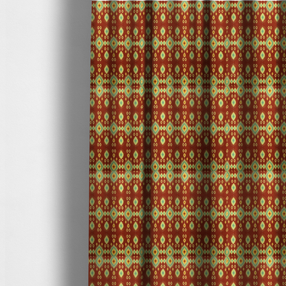 the fabric used to create these made-to-measure curtains is a print featuring a repeating vertical ikat pattern. The design showcases distinct diamond and teardrop motifs with feathered edges in soft sage green, teal, and mustard yellow over a solid terracotta red background.
