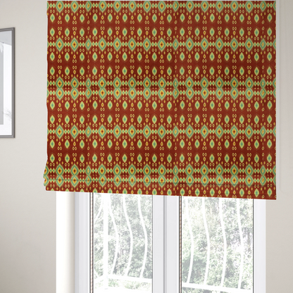 The fabric used to create these Roman blinds is a print featuring a repeating vertical ikat pattern. The design showcases distinct diamond and teardrop motifs with feathered edges in soft sage green, teal, and mustard yellow over a solid terracotta red background.