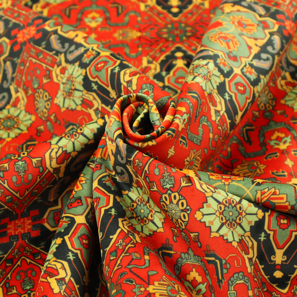 Fabric print featuring an intricate, repeating Persian rug or Moroccan mosaic design. The pattern displays large geometric medallions and scrolling damask shapes in vibrant red, jade green, and warm gold.
