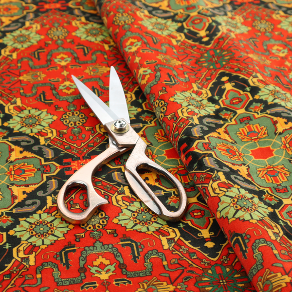 Fabric print featuring an intricate, repeating Persian rug or Moroccan mosaic design. The pattern displays large geometric medallions and scrolling damask shapes in vibrant red, jade green, and warm gold.