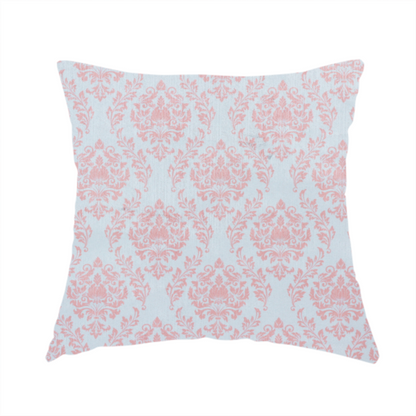 The fabric used to create this handmade cushion is a print featuring a classic, repeating vintage damask pattern. The traditional ornate floral and acanthus leaf motifs are printed in a soft blush pink over a light, pastel icy blue background.