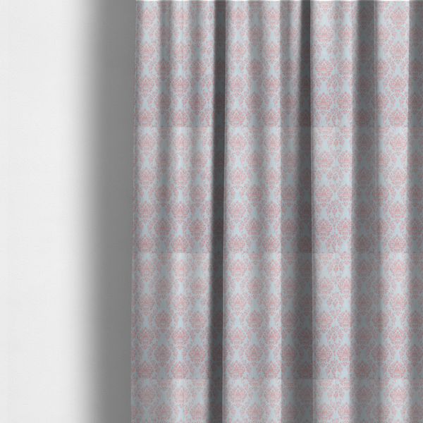 The fabric used to create these made-to-measure curtains is a print featuring a classic, repeating vintage damask pattern. The traditional ornate floral and acanthus leaf motifs are printed in a soft blush pink over a light, pastel icy blue background.