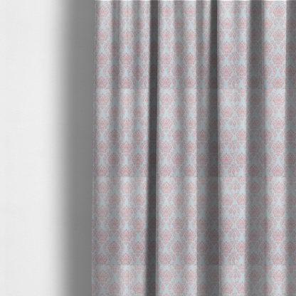 The fabric used to create these made-to-measure curtains is a print featuring a classic, repeating vintage damask pattern. The traditional ornate floral and acanthus leaf motifs are printed in a soft blush pink over a light, pastel icy blue background.