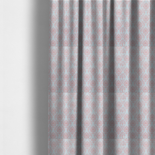 The fabric used to create these made-to-measure curtains is a print featuring a classic, repeating vintage damask pattern. The traditional ornate floral and acanthus leaf motifs are printed in a soft blush pink over a light, pastel icy blue background.