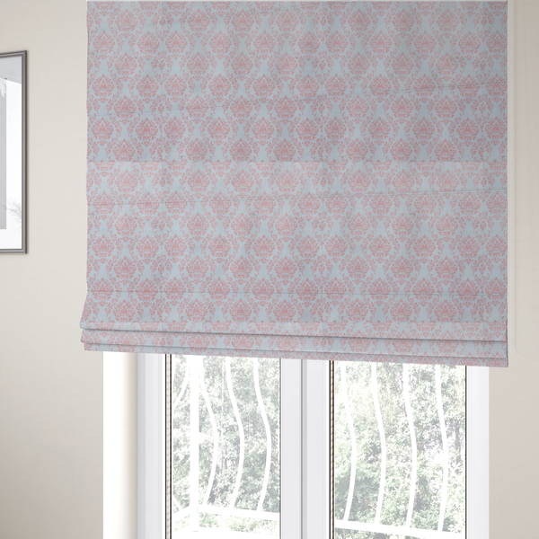 The fabric used to create these Roman blinds is a print featuring a classic, repeating vintage damask pattern. The traditional ornate floral and acanthus leaf motifs are printed in a soft blush pink over a light, pastel icy blue background.