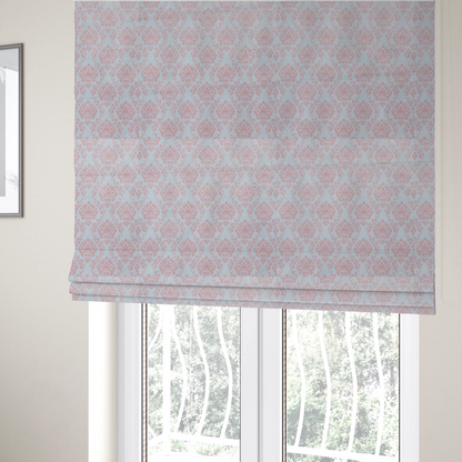 The fabric used to create these Roman blinds is a print featuring a classic, repeating vintage damask pattern. The traditional ornate floral and acanthus leaf motifs are printed in a soft blush pink over a light, pastel icy blue background.