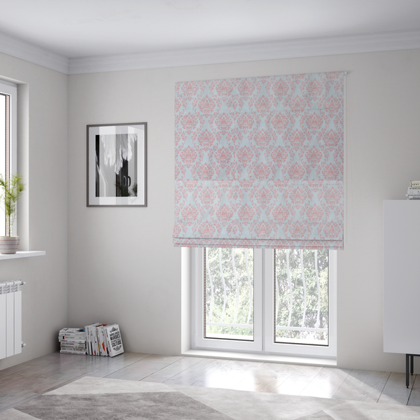 The fabric used to create these Roman blinds is a print featuring a classic, repeating vintage damask pattern. The traditional ornate floral and acanthus leaf motifs are printed in a soft blush pink over a light, pastel icy blue background.