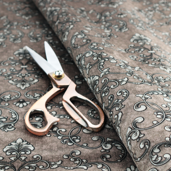 Fabric featuring a repeating traditional damask pattern in white and dark grey outlines over a textured, light taupe background.