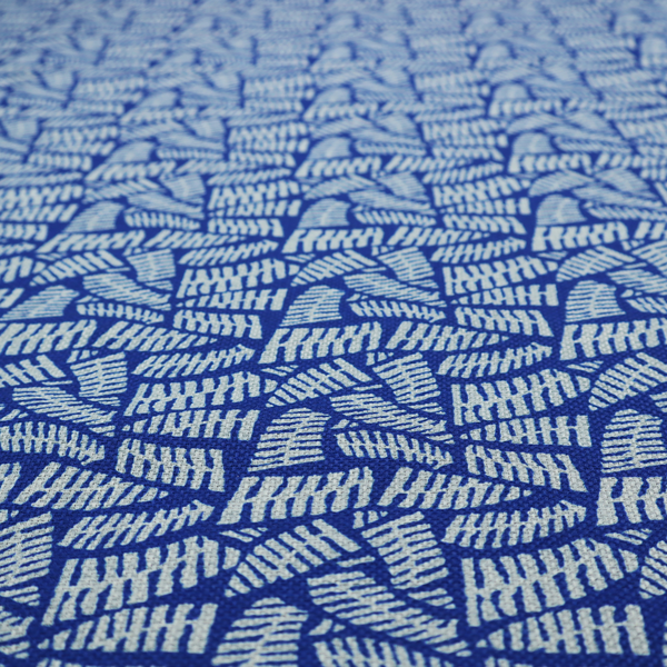 Fabric featuring a vibrant, repeating geometric pattern of light grey, abstract leaf or comb-like blocks closely packed on a royal blue background.