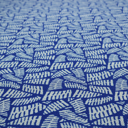 Fabric featuring a vibrant, repeating geometric pattern of light grey, abstract leaf or comb-like blocks closely packed on a royal blue background.