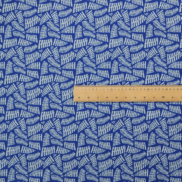 Fabric featuring a vibrant, repeating geometric pattern of light grey, abstract leaf or comb-like blocks closely packed on a royal blue background.