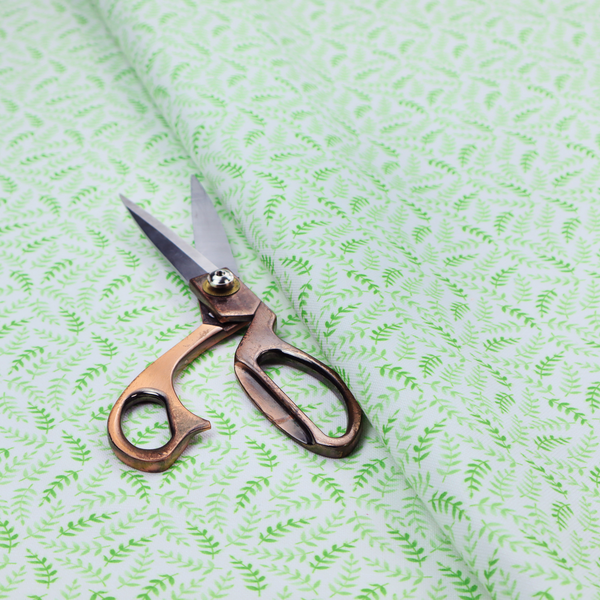 Fabric featuring a dense, repeating pattern of small, vibrant lime green leafy sprigs and fern-like fronds on a crisp white background.