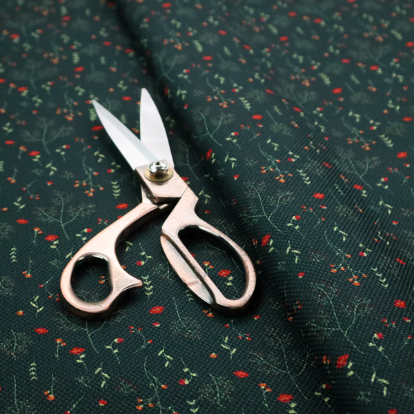 Dark forest green fabric featuring a delicate, scattered botanical print. The pattern includes fine, wispy light green twigs, tiny light green leaves, and small, vibrant red wildflowers and buds spread evenly across the textured dark background.