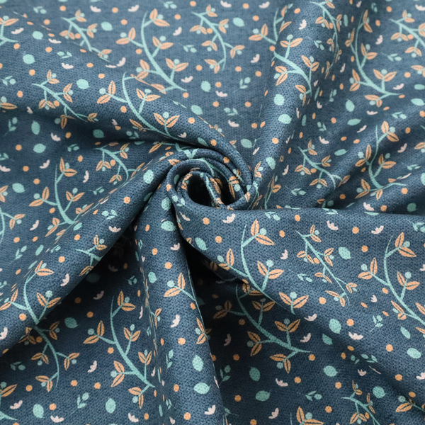 Slate blue textured fabric with a delicate ditsy botanical print. The repeating pattern features thin, curved mint green vine stems with small peach-coloured leaves, surrounded by tiny scattered peach polka dots and miniature teal leaf accents throughout the design.