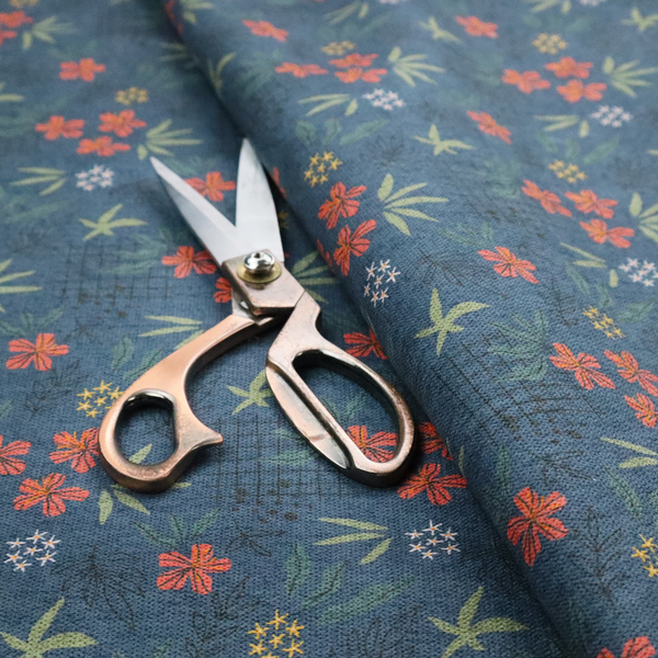 Deep teal blue fabric featuring a subtle crosshatch texture and a tropical botanical print. The repeating pattern showcases clusters of small rust-coral flowers, sage green palm fronds, and scattered miniature yellow starburst blooms.
