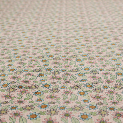 Textured dusty blush pink fabric with a dense retro calico print. The intricate pattern features small, sketch-style daisies with mustard yellow centres and blue-teal petals, mixed with pink blooms and delicate sage green leaves spread tightly across the surface.