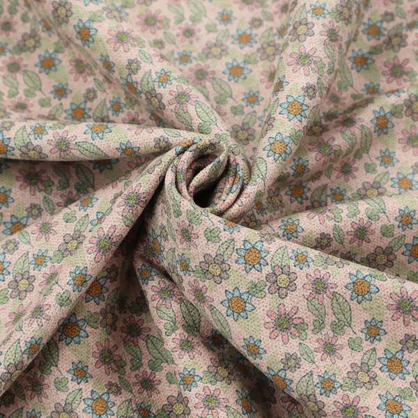 Textured dusty blush pink fabric with a dense retro calico print. The intricate pattern features small, sketch-style daisies with mustard yellow centres and blue-teal petals, mixed with pink blooms and delicate sage green leaves spread tightly across the surface.