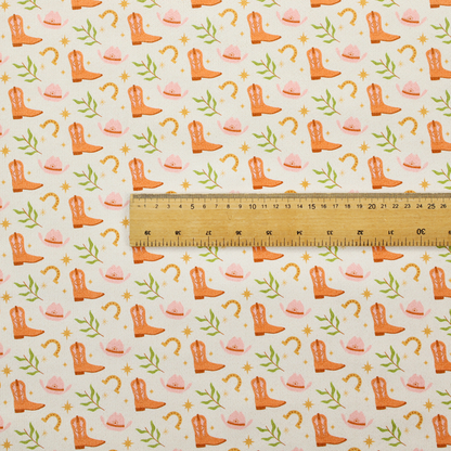 A repeating pattern of cowboy-themed illustrations on a cream-coloured fabric backdrop. The design features light orange cowboy boots, pale pink cowboy hats, golden horseshoes, small green leafy sprigs, and delicate four-pointed stars scattered throughout.