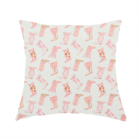 The fabric used to create this handmade cushion is a repeating seamless pattern featuring an assortment of illustrated cowboy and cowgirl boots against a clean, off-white background. The boots are rendered in a soft, whimsical style with a colour palette consisting of various shades of pink, cream, light tan, and occasional brown accents.