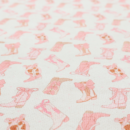 A repeating seamless pattern featuring an assortment of illustrated cowboy and cowgirl boots against a clean, off-white background. The boots are rendered in a soft, whimsical style with a colour palette consisting of various shades of pink, cream, light tan, and occasional brown accents.