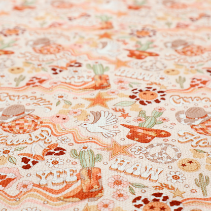 A vibrant, repeating pattern blending 1970s retro elements with a western aesthetic, set against a light cream-colored background. The design uses a warm colour palette of terracotta orange, muted mustard yellow, sage green, and soft tan.