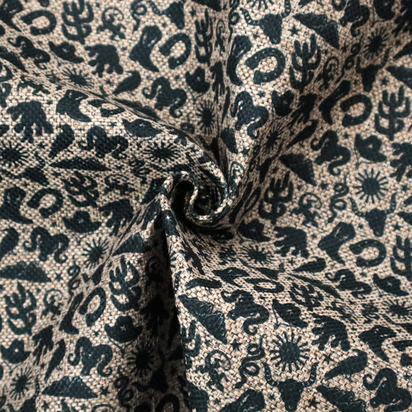 A dense, repeating pattern featuring black graphic silhouettes of classic southwestern and western elements printed on a heavily textured, woven beige fabric base.