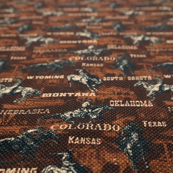 A dark, moody, repeating western tapestry pattern featuring realistic, vintage-style illustrations of cowboys on horseback, set against a deeply textured dark brown background. The palette relies on rich chocolate brown, earthy terracotta tones, and contrast details in cream and muted slate blue.