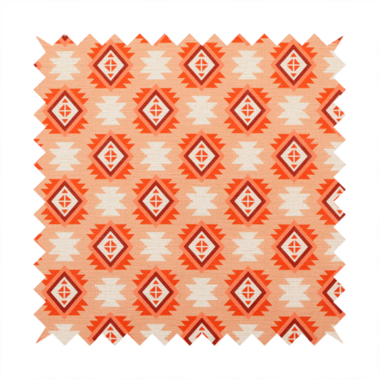 A uniform, repeating geometric pattern featuring southwestern and tribal-inspired motifs printed on a linen-textured background. The colour palette relies on warm, sun-baked tones, including a soft peach backdrop, vibrant terracotta orange, rust brown, and cream accents.