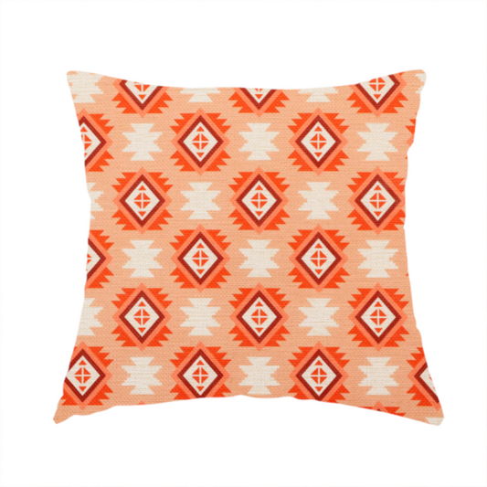 The fabric used to create this handmade cushion is a uniform, repeating geometric pattern featuring southwestern and tribal-inspired motifs printed on a linen-textured background. The colour palette relies on warm, sun-baked tones, including a soft peach backdrop, vibrant terracotta orange, rust brown, and cream accents.