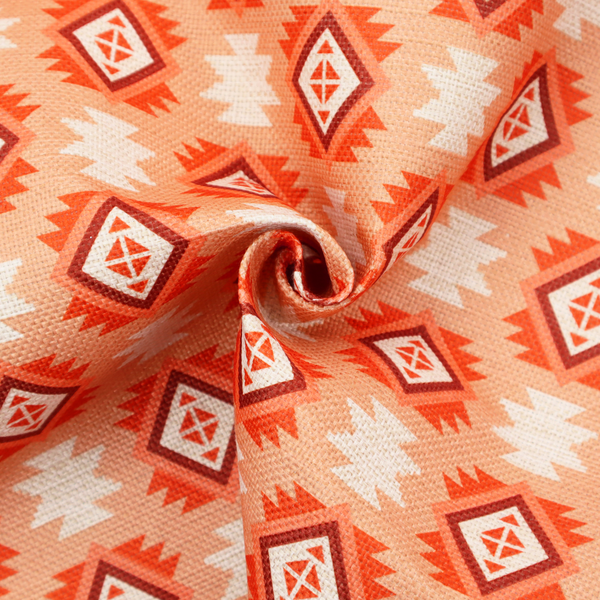 A uniform, repeating geometric pattern featuring southwestern and tribal-inspired motifs printed on a linen-textured background. The colour palette relies on warm, sun-baked tones, including a soft peach backdrop, vibrant terracotta orange, rust brown, and cream accents.