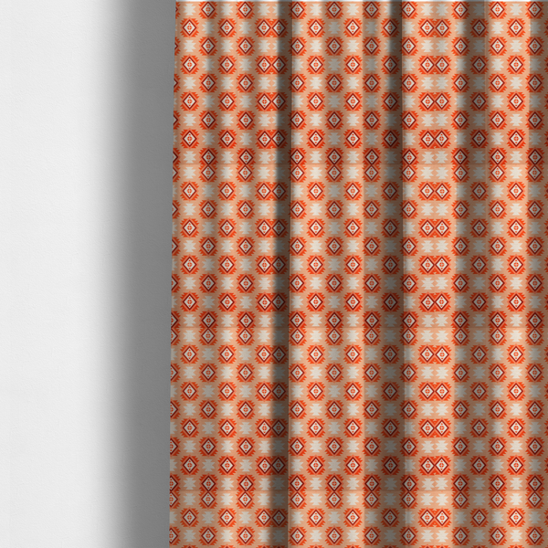 The fabric used to create these made-to-measure curtains is a uniform, repeating geometric pattern featuring southwestern and tribal-inspired motifs printed on a linen-textured background. The colour palette relies on warm, sun-baked tones, including a soft peach backdrop, vibrant terracotta orange, rust brown, and cream accents.