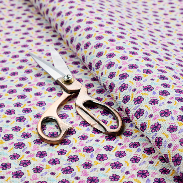A dense, small-scale ditsy floral print. The pattern is composed of miniature five-petal magenta flowers outlined in dark purple, scattered symmetrically alongside tiny pastel pink blossoms, lavender leaves, and small ochre yellow botanical accents across a light, textured off-white background.