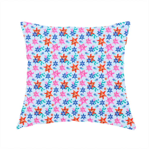 The fabric used to create this handmade cushion is a dense, small-scale tropical ditsy pattern. The design consists of repeating star-shaped lily blossoms in bright shades of orange, magenta pink, and medium blue, accented with tiny teal green leafy sprigs and miniature blue flowers, all distributed across a solid light sky-blue background.