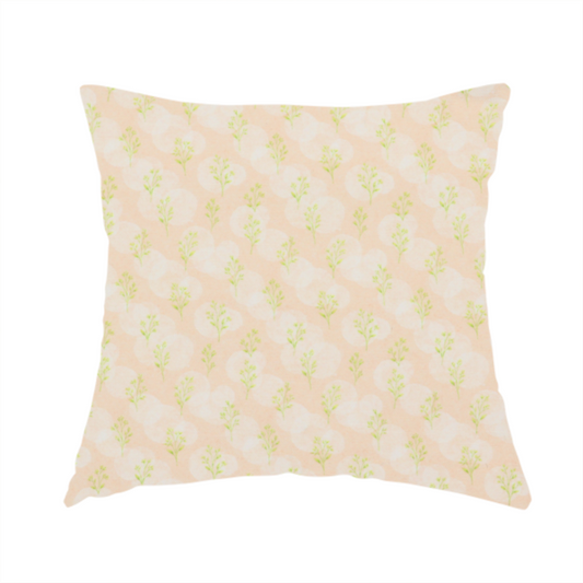 The fabric used to create this handmade cushion is a soft watercolour design. The background consists of a subtle pastel peach wash layered with faint, painterly off-white circular polka dots. Arranged in neat diagonal rows over the circles are miniature, light lime green botanical sprigs and fine leaf stems.