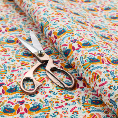 A Scandinavian folk art pattern. The design features symmetrical pairs of stylized teal and golden-yellow lovebirds facing each other under a small striped heart. They are surrounded by an intricate all-over arrangement of tiny multi-coloured wildflowers, hearts, and vines in shades of orange, magenta, yellow, and blue over a textured, off-white background.