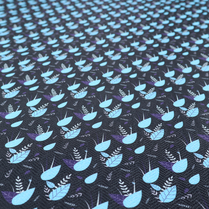 A dense, miniature botanical print. The design features small, light ice-blue teardrop shapes resembling abstract petals or water droplets, paired with tiny light blue textured leaves and white sprigs. The pattern is scattered over a dark charcoal grey background that features a subtle, woven herringbone texture.