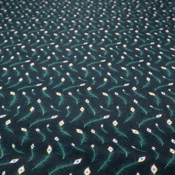 A dense, elegant peacock feather motif. The design showcase a repetitive pattern of small, curved green peacock feathers with bright orange, blue, and white "eyes" floating diagonally. The pattern is set against a dark charcoal grey background that has a subtle, woven herringbone texture.