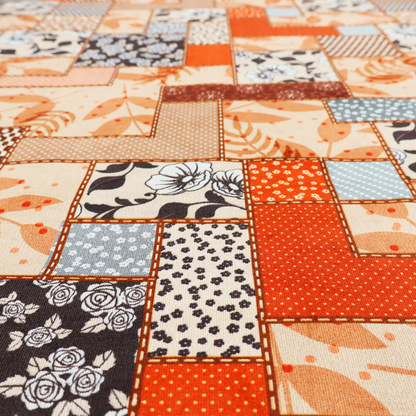 A patchwork fabric pattern featuring a mix of rectangular blocks with floral prints, polka dots, autumn leaves, and geometric shapes in orange, beige, brown, and black-and-white.