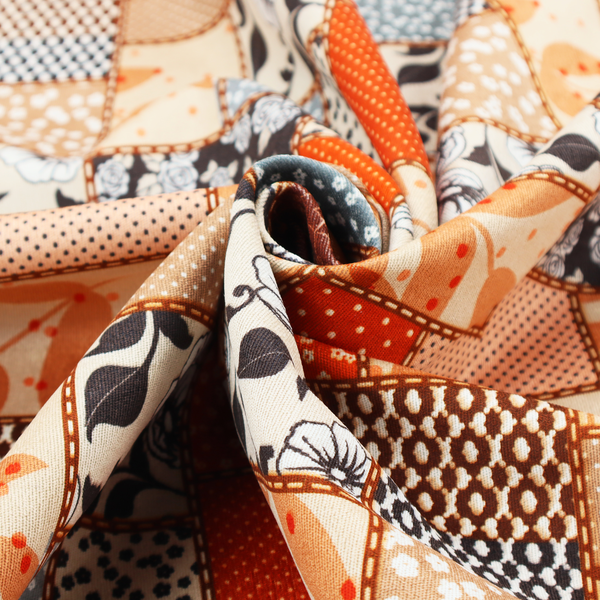 A patchwork fabric pattern featuring a mix of rectangular blocks with floral prints, polka dots, autumn leaves, and geometric shapes in orange, beige, brown, and black-and-white.