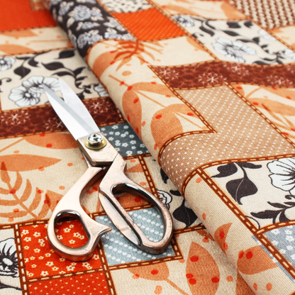A patchwork fabric pattern featuring a mix of rectangular blocks with floral prints, polka dots, autumn leaves, and geometric shapes in orange, beige, brown, and black-and-white.