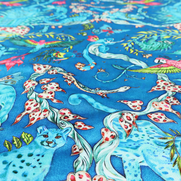 A vibrant turquoise blue fabric featuring an intricate, symmetrical maximalist print of a mythical tropical rainforest. Large, ethereal blue tigers with pink accents are flanked by dense fronds. The repeating pattern is filled with exotic jungle wildlife, including leopards, sloths hanging from vines, winged monkeys, bats, and colourful macaws in shades of bright pink and lime green.