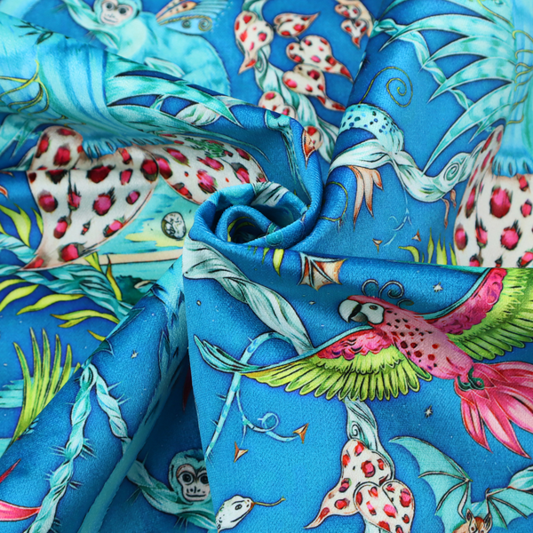 A vibrant turquoise blue fabric featuring an intricate, symmetrical maximalist print of a mythical tropical rainforest. Large, ethereal blue tigers with pink accents are flanked by dense fronds. The repeating pattern is filled with exotic jungle wildlife, including leopards, sloths hanging from vines, winged monkeys, bats, and colourful macaws in shades of bright pink and lime green.