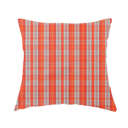 The fabric used to create this handmade cushion is a bright plaid fabric pattern featuring thin, intersecting stripes of orange, light teal, and yellow on a textured background.