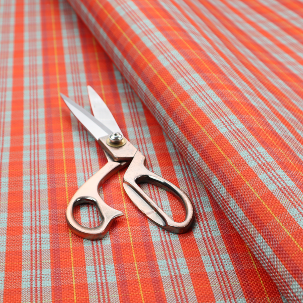 A bright plaid fabric pattern featuring thin, intersecting stripes of orange, light teal, and yellow on a textured background.