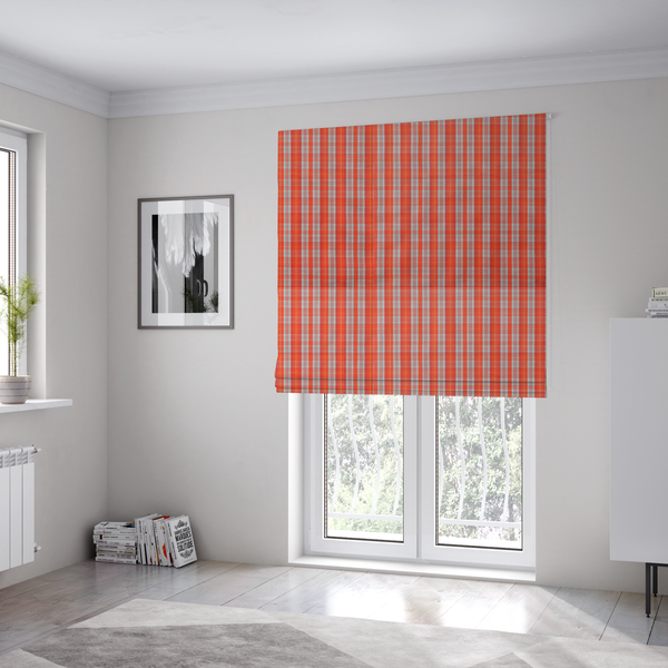 The fabric used to create these Roman blinds is a bright plaid fabric pattern featuring thin, intersecting stripes of orange, light teal, and yellow on a textured background.