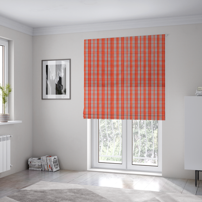 The fabric used to create these Roman blinds is a bright plaid fabric pattern featuring thin, intersecting stripes of orange, light teal, and yellow on a textured background.