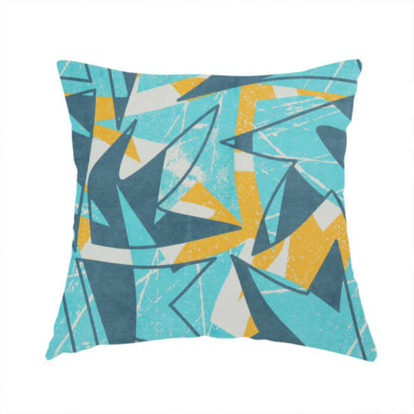 The fabric used to create this handmade cushion is a bold, retro geometric pattern with abstract, sharp arrow and shard shapes in turquoise, slate blue, mustard yellow, and white with a distressed texture.