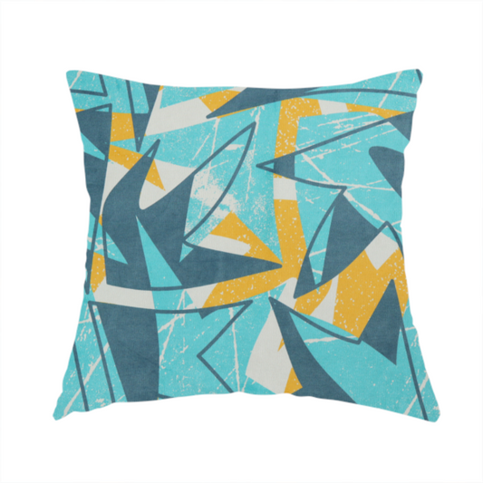 The fabric used to create this handmade cushion is a bold, retro geometric pattern with abstract, sharp arrow and shard shapes in turquoise, slate blue, mustard yellow, and white with a distressed texture.