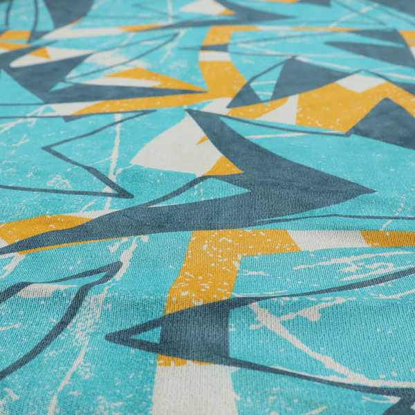 Fabric featuring a bold, retro geometric pattern with abstract, sharp arrow and shard shapes in turquoise, slate blue, mustard yellow, and white with a distressed texture.